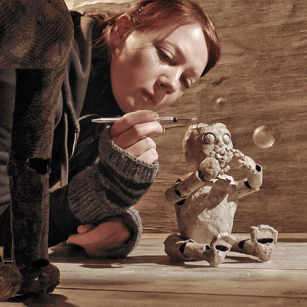 On-set photograph of Sophie applying the papier-mâché material onto the child puppet
